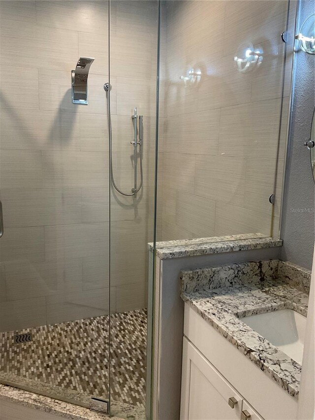 bathroom featuring a shower with door and vanity