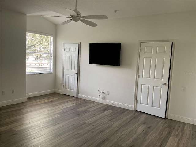 interior space with a ceiling fan, baseboards, vaulted ceiling, and wood finished floors