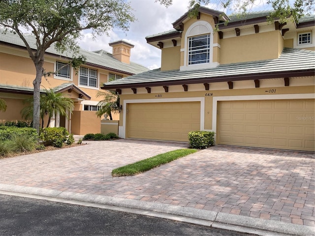 view of front facade featuring a tile roof, decorative driveway, and stucco siding