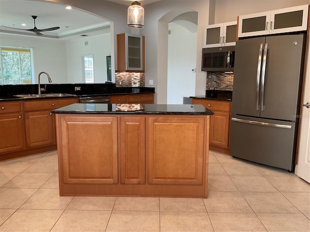 kitchen featuring a center island, light tile patterned floors, stainless steel appliances, a sink, and ceiling fan