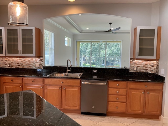 kitchen featuring a sink, a ceiling fan, ornamental molding, stainless steel dishwasher, and dark stone countertops