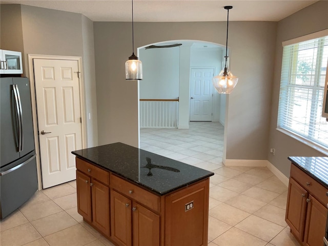 kitchen with arched walkways, a wealth of natural light, freestanding refrigerator, and a center island