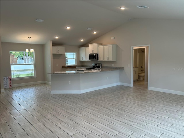 kitchen with appliances with stainless steel finishes, pendant lighting, white cabinets, kitchen peninsula, and light stone countertops