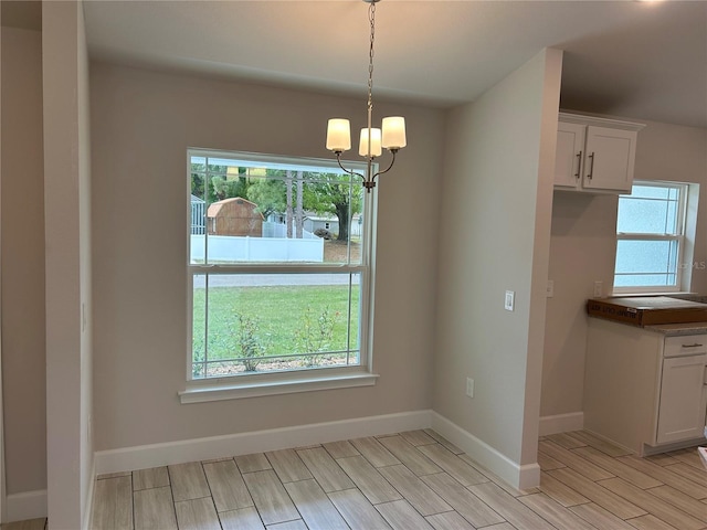 unfurnished dining area featuring a wealth of natural light and an inviting chandelier