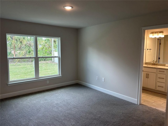 unfurnished bedroom featuring ensuite bathroom, sink, and light colored carpet