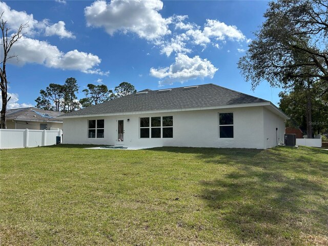 rear view of property with central AC and a lawn