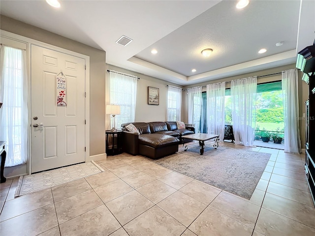 living room featuring a tray ceiling and light tile patterned floors