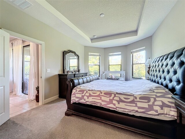 carpeted bedroom featuring a tray ceiling and a textured ceiling