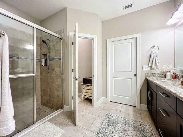 bathroom featuring tile patterned flooring, vanity, and walk in shower