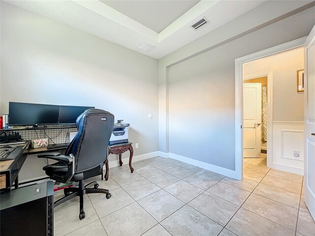 office featuring a tray ceiling and light tile patterned floors