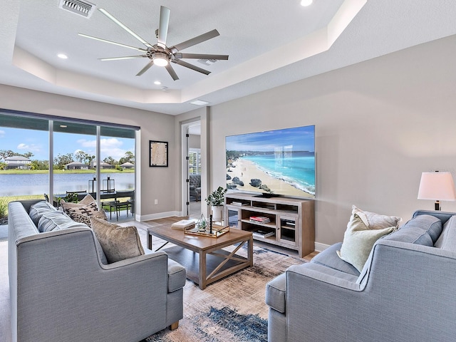 living room featuring a tray ceiling, ceiling fan, and a textured ceiling