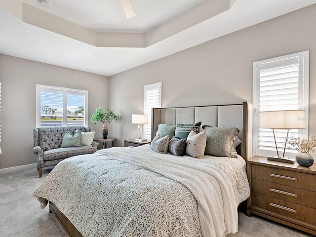 bedroom featuring ceiling fan, light colored carpet, and a raised ceiling