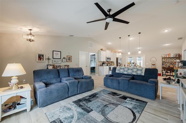 living room featuring vaulted ceiling, ceiling fan with notable chandelier, and light hardwood / wood-style floors