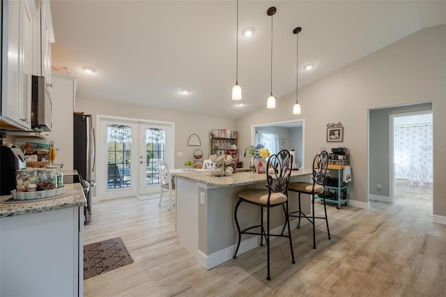 kitchen with white cabinetry, french doors, hanging light fixtures, vaulted ceiling, and light hardwood / wood-style floors