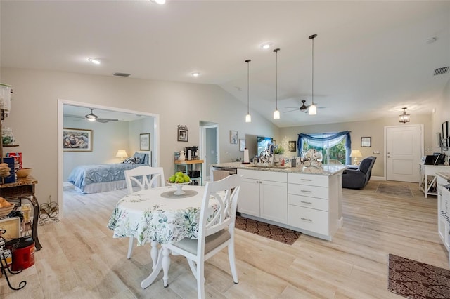 kitchen with light stone countertops, hanging light fixtures, ceiling fan, lofted ceiling, and light hardwood / wood-style floors