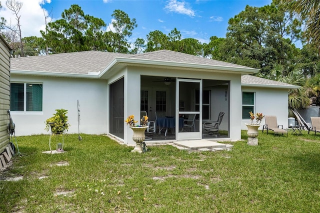 rear view of property featuring a lawn and ceiling fan