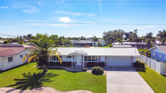 ranch-style home featuring metal roof, driveway, a front yard, and fence