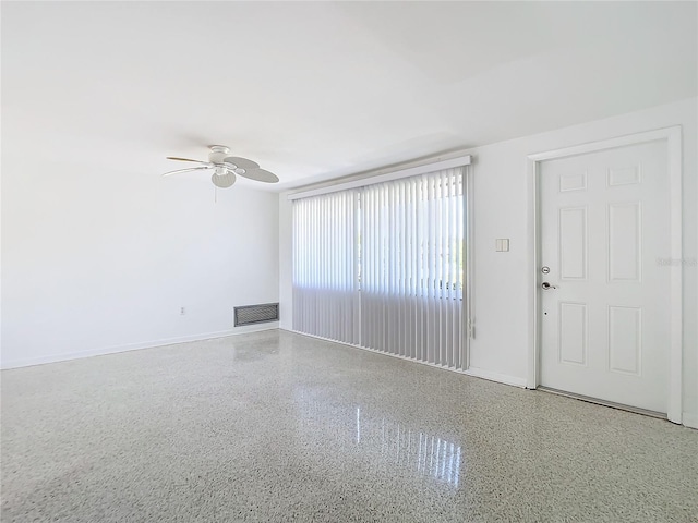 unfurnished room featuring ceiling fan, speckled floor, visible vents, and baseboards