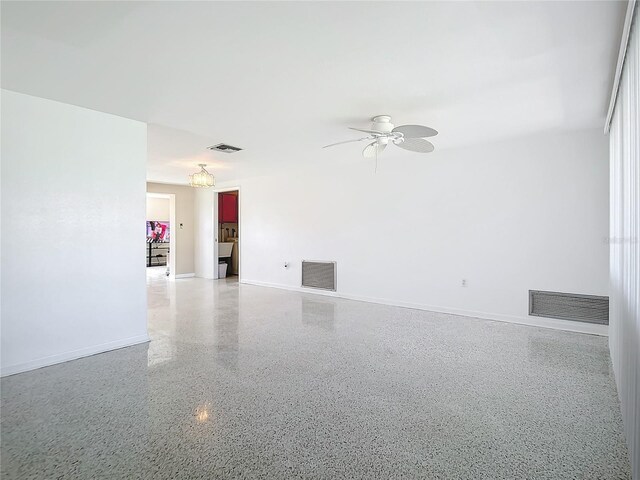 empty room featuring baseboards, visible vents, and light speckled floor