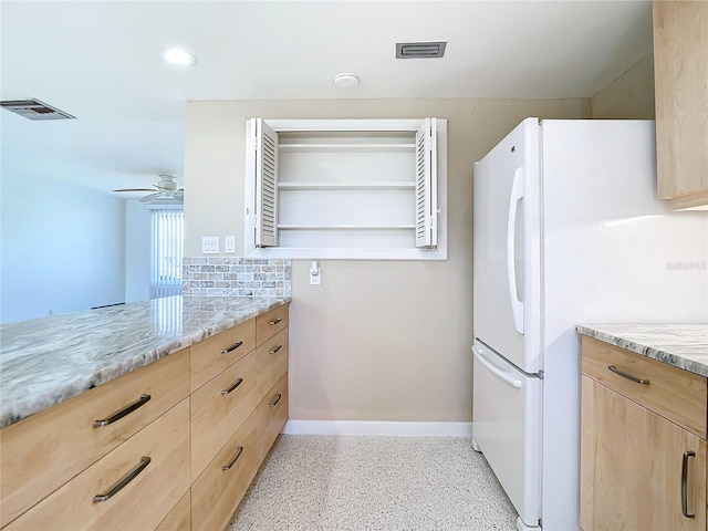 kitchen featuring white refrigerator, light stone countertops, and light brown cabinets