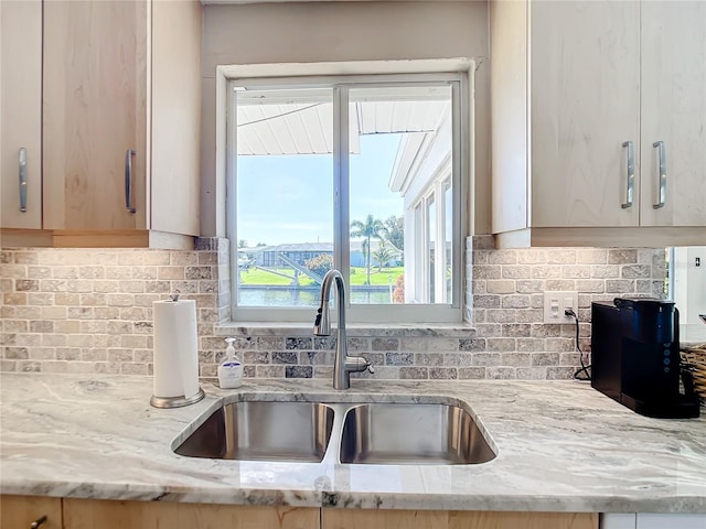 kitchen with light brown cabinetry, light stone counters, sink, and decorative backsplash