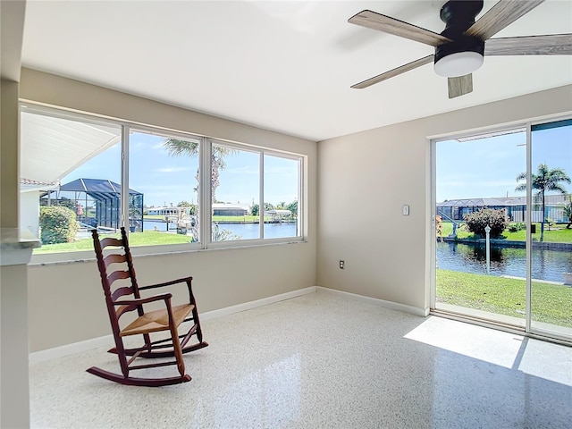 living area featuring a water view, ceiling fan, baseboards, and light speckled floor