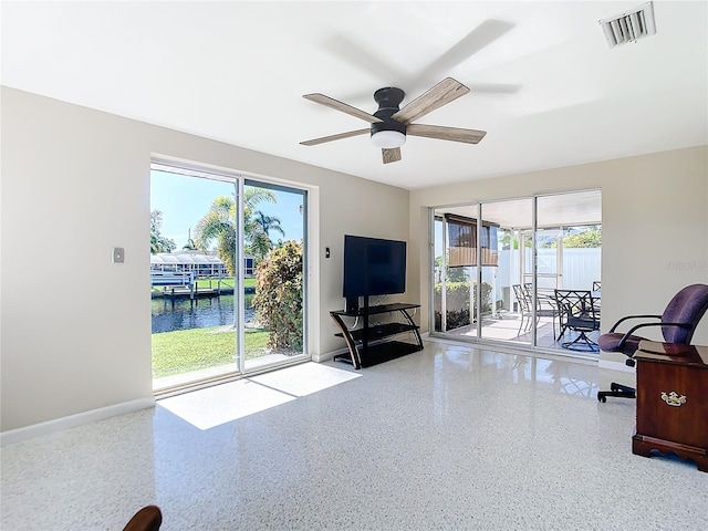 living room with ceiling fan, baseboards, visible vents, and light speckled floor