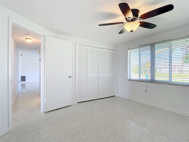 unfurnished bedroom with light speckled floor, ceiling fan, a closet, and baseboards