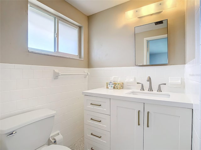 bathroom featuring tile walls, a wainscoted wall, vanity, and toilet