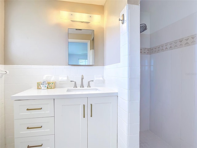 bathroom with tiled shower, tile walls, tasteful backsplash, and vanity