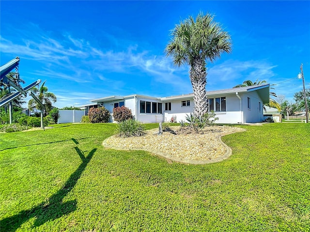 rear view of property featuring a yard, fence, and stucco siding