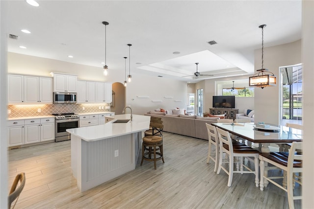 kitchen with white cabinets, appliances with stainless steel finishes, light hardwood / wood-style flooring, and a healthy amount of sunlight