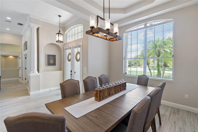 dining area with decorative columns, crown molding, light hardwood / wood-style flooring, and french doors