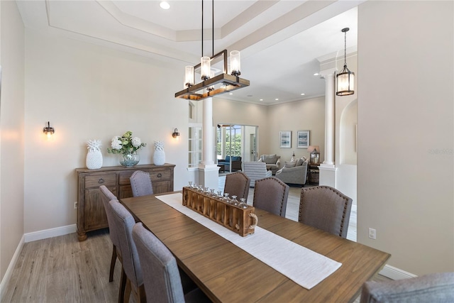 dining space with ornate columns, ornamental molding, and light wood-type flooring