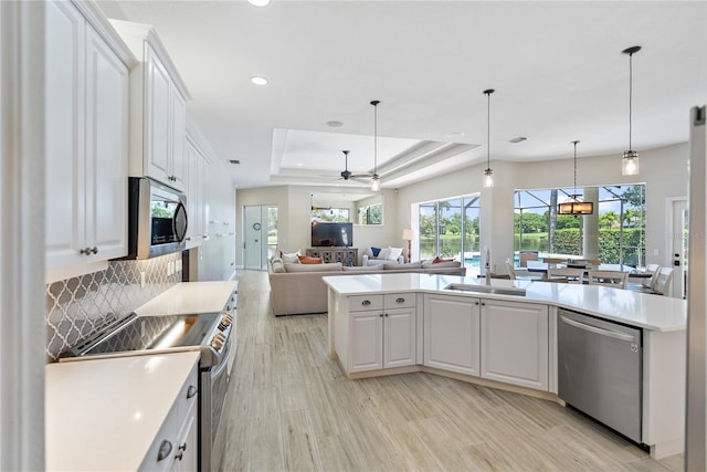 kitchen featuring appliances with stainless steel finishes, a raised ceiling, ceiling fan, light hardwood / wood-style flooring, and white cabinetry