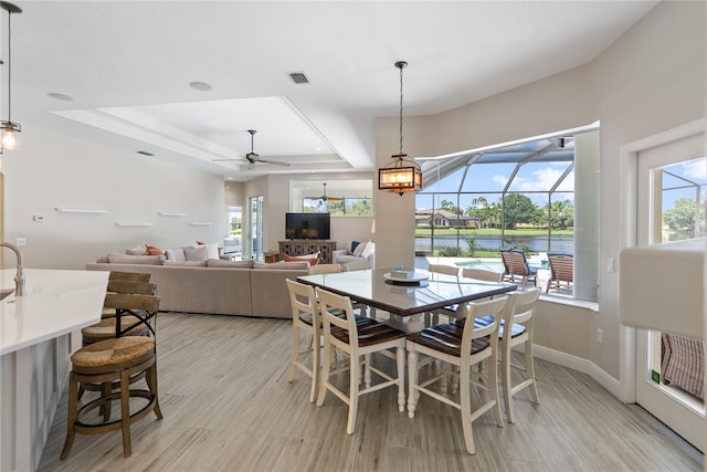 dining room featuring a raised ceiling, ceiling fan, plenty of natural light, and light hardwood / wood-style floors