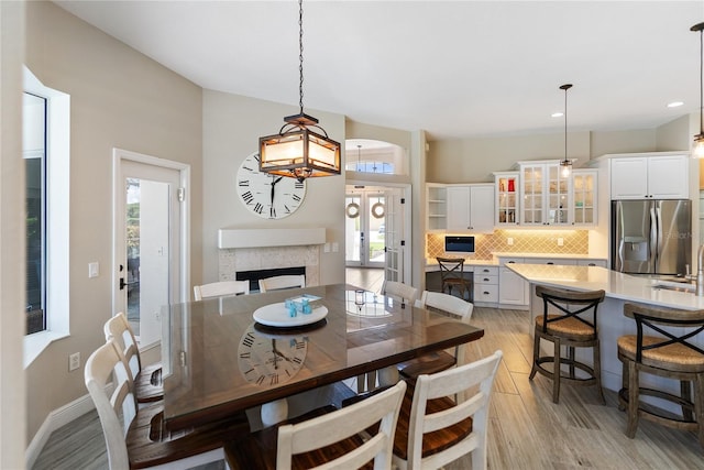 dining area featuring french doors, light wood-type flooring, a healthy amount of sunlight, and sink