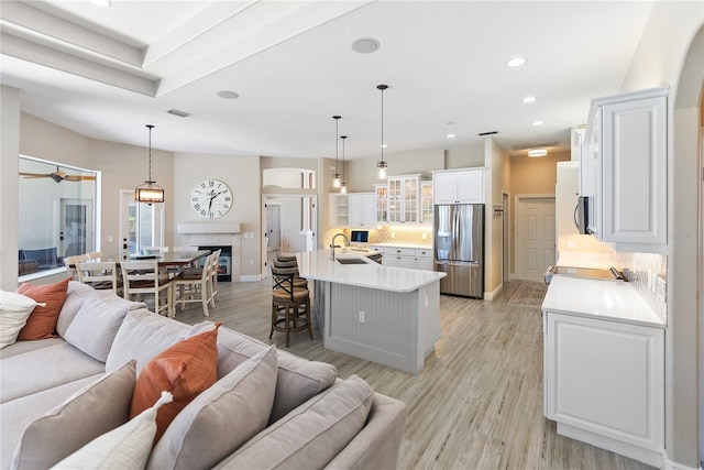 living room with ceiling fan, sink, and light hardwood / wood-style flooring