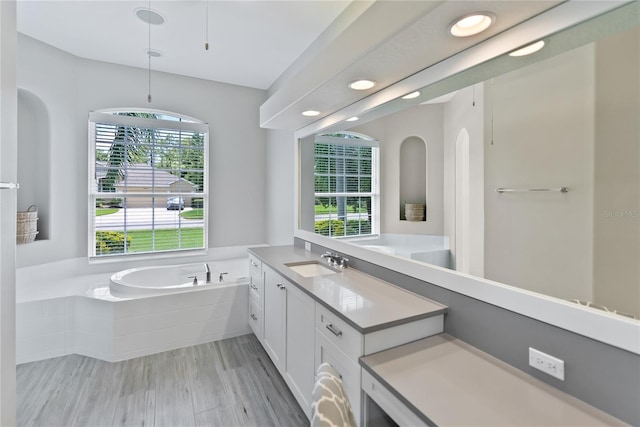 bathroom with vanity, wood-type flooring, and tiled bath