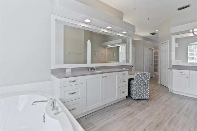 bathroom with hardwood / wood-style flooring, vanity, and a tub