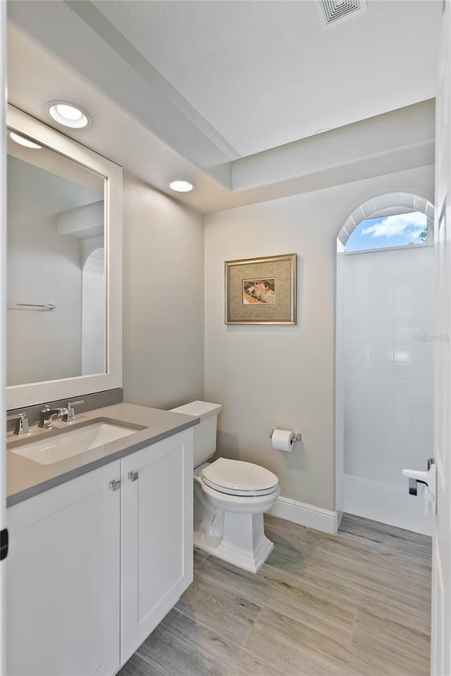 bathroom featuring a shower, vanity, hardwood / wood-style flooring, and toilet