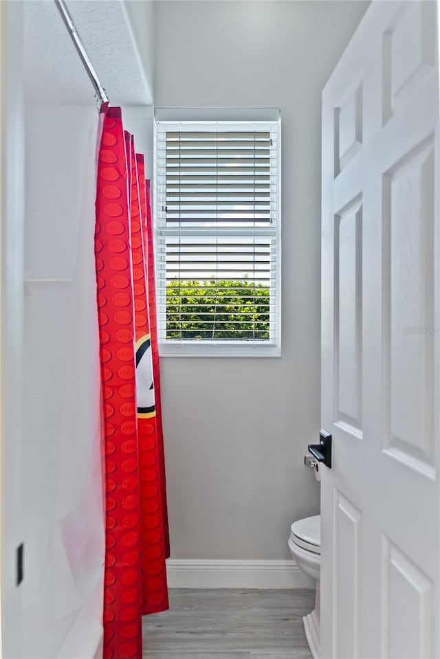 bathroom featuring hardwood / wood-style floors, curtained shower, and toilet