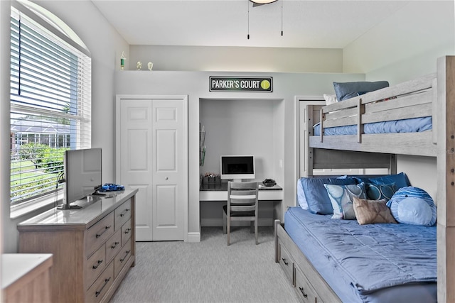 carpeted bedroom featuring a closet and built in desk