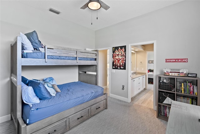 bedroom featuring light carpet, connected bathroom, and ceiling fan