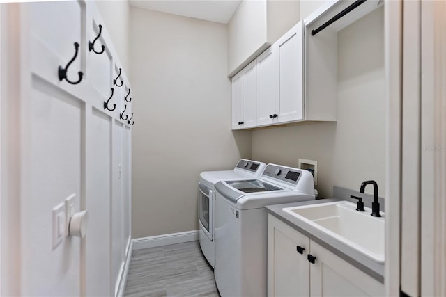 clothes washing area with sink, light hardwood / wood-style flooring, cabinets, and independent washer and dryer