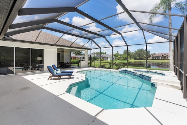 view of pool with ceiling fan, a lanai, an in ground hot tub, a water view, and a patio