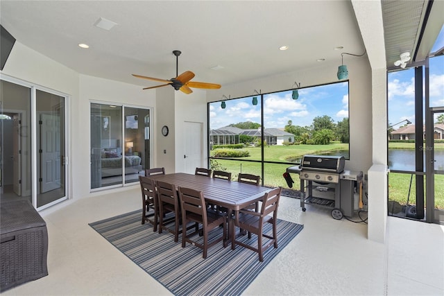 sunroom / solarium featuring a wealth of natural light, a water view, and ceiling fan