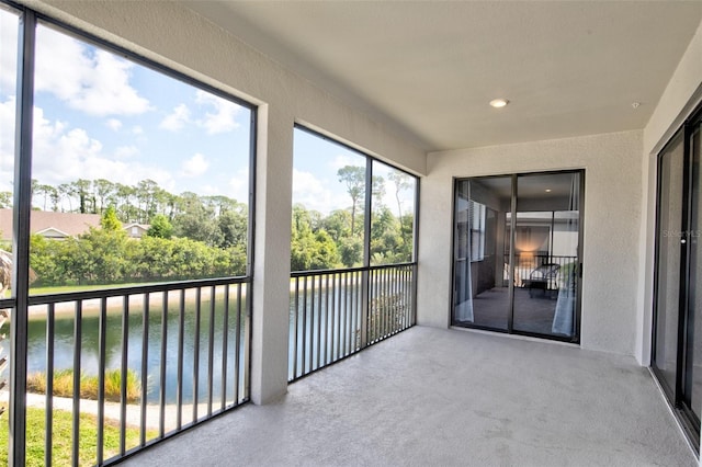 unfurnished sunroom with a water view and a textured wall