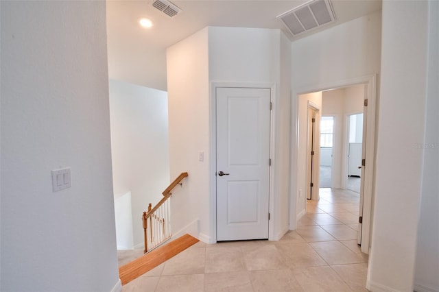 hallway featuring an upstairs landing, light tile patterned flooring, and baseboards