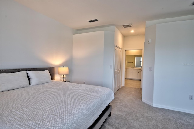 bedroom featuring a closet, light colored carpet, and connected bathroom